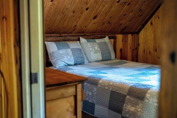 Une chambre confortable avec un plafond en bois et un lit recouvert d  ’une couette à carreaux.