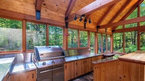 Une cabane en bois dotée d’un barbecue intégré et d’un revêtement de sol en pierre.