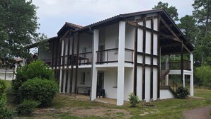 A two-story building with a balcony on the upper floor, surrounded by greenery. - Apartment in Landes for 6/7 persons, pet friendly (Ondres)