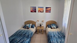 A small, clean room with two single beds, a small table, and three paintings on the wall. - Apartment in Landes for 6/7 persons, pet friendly (Ondres)