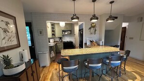 A modern kitchen with a central island, bar stools, and pendant lighting.