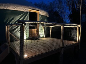 Un espacio al aire libre cubierto con un cerramiento de mosquitero, una puerta y una fuente de luz.