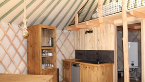 A compact kitchen with wooden cabinets, a dishwasher, and a small countertop. - Yurt rental 2 / 4 / 6 persons (Saint-Amans-des-Cots)