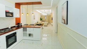 Een moderne keuken met een centraal eiland, inbouwapparatuur en hanglampen.