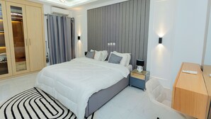 Een moderne slaapkamer met een groot bed, een kledingkast, een bureau en een stoel.