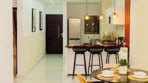 Een moderne keuken met een centraal eiland, zwarte barstoelen en hanglampen.