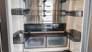 An open refrigerator with transparent shelves and a freezer compartment. - Ultra-modern penthouse apartment (Brunnthal)