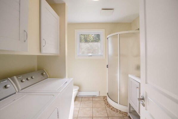A laundry room with a washer and dryer, a window, and a shower area. - Waterfront Chalet: Kayak, Hot Tub & Fire Pit (Saint-Raymond)