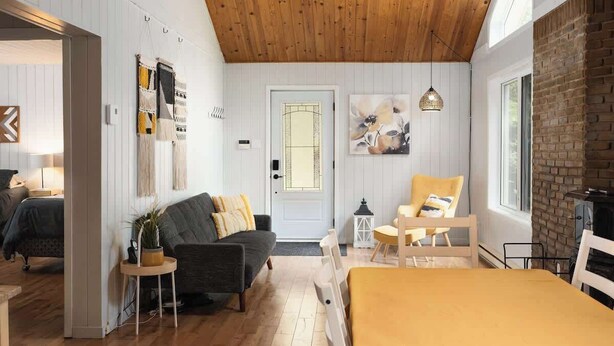 Une pièce chaleureuse avec un plafond en bois, un lit, un canapé, un fauteuil et une cheminée.