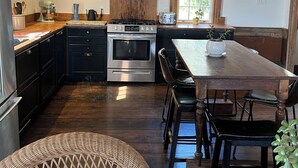 Una cocina con armarios de madera oscura, una isla grande con asientos, una estufa a gas y un horno de acero inoxidable.