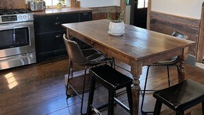 Una cocina rústica con una mesa de madera, sillas y un ventanal grande.
