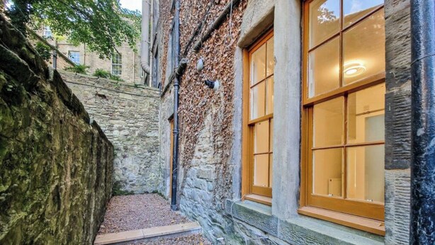 Un estrecho pasillo de piedra con una puerta y una ventana de madera.