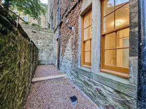 A narrow stone corridor with a wooden door and a window with a wooden frame.