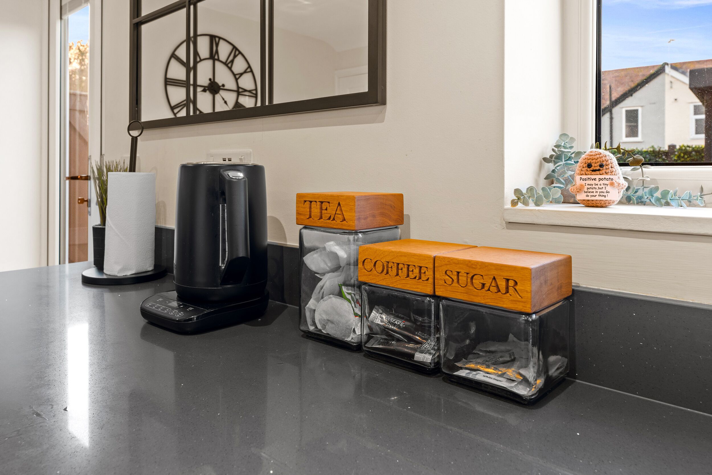 A kitchen counter with a coffee maker, a tea box, and a sugar box.
