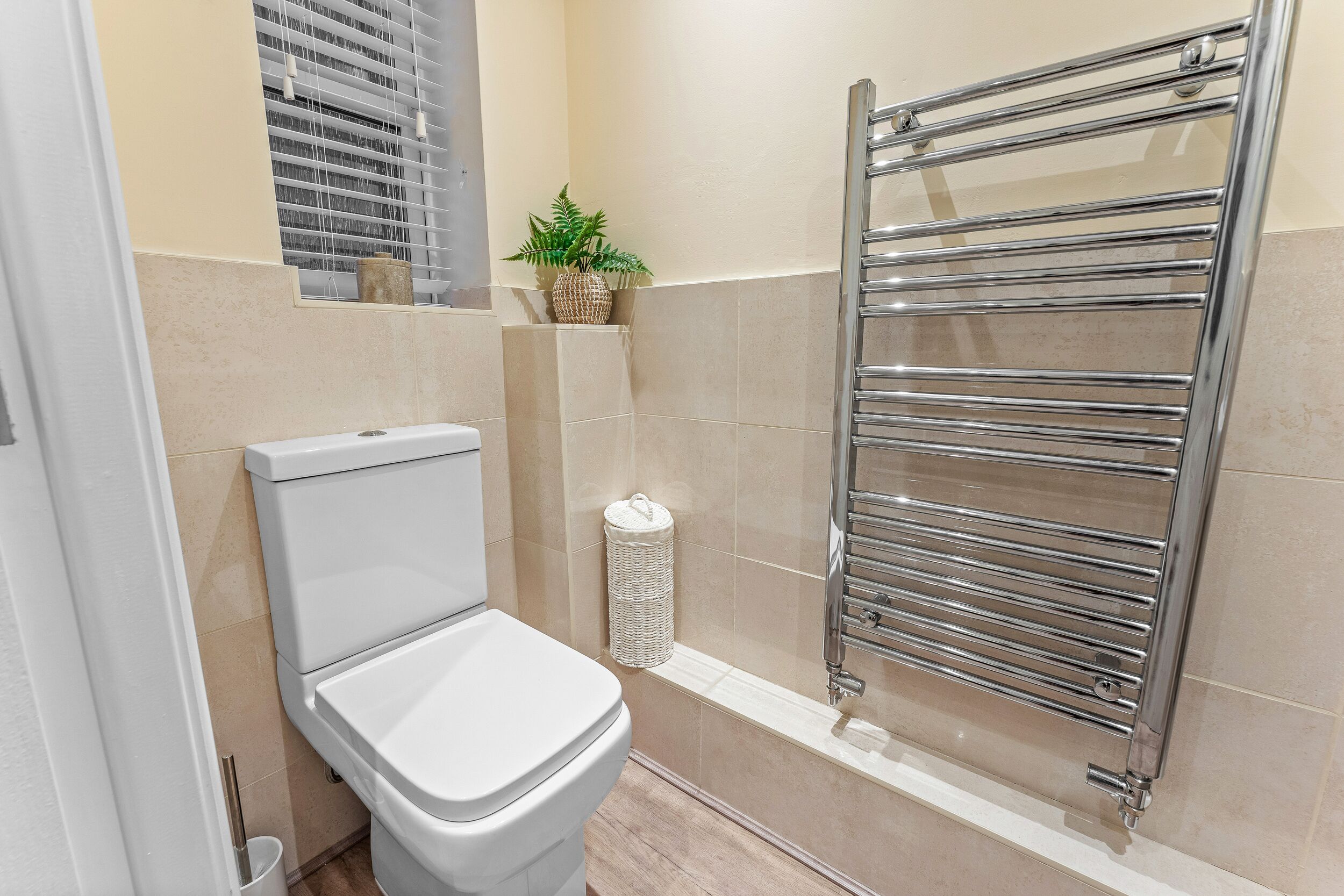 Une salle de bain avec des toilettes, un porte-serviettes chromé et une plante en pot accrochée au mur.