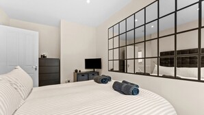 A bedroom with a large bed, a television, a dresser, and a mirror. - Hafan Rhos (Colwyn Bay)