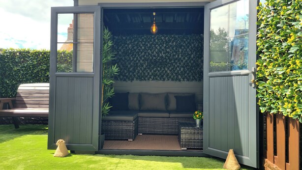 A modern outdoor seating area with a built-in bench, a small table with a plant, and a decorative light fixture. - Hafan Rhos (Colwyn Bay)