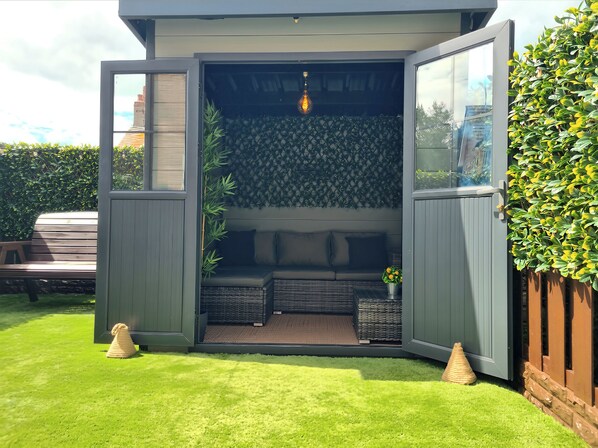 A modern outdoor seating area with a built-in bench, a small table with a plant, and a decorative light fixture.