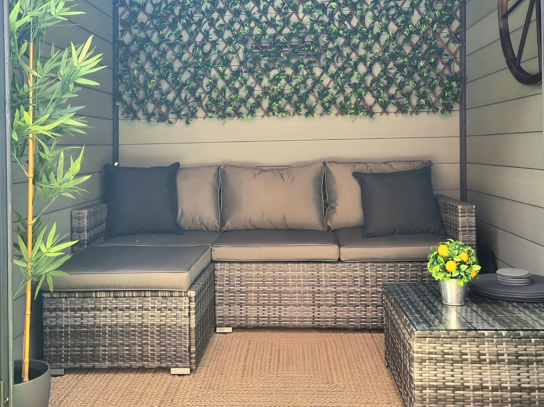 A sectional sofa with cushions, a woven coffee table, a wall-mounted plant, and a bamboo plant.