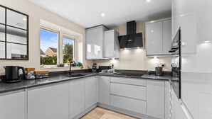 A modern kitchen with grey cabinets, a black countertop, and a window providing a view of the outside. - Hafan Rhos (Colwyn Bay)