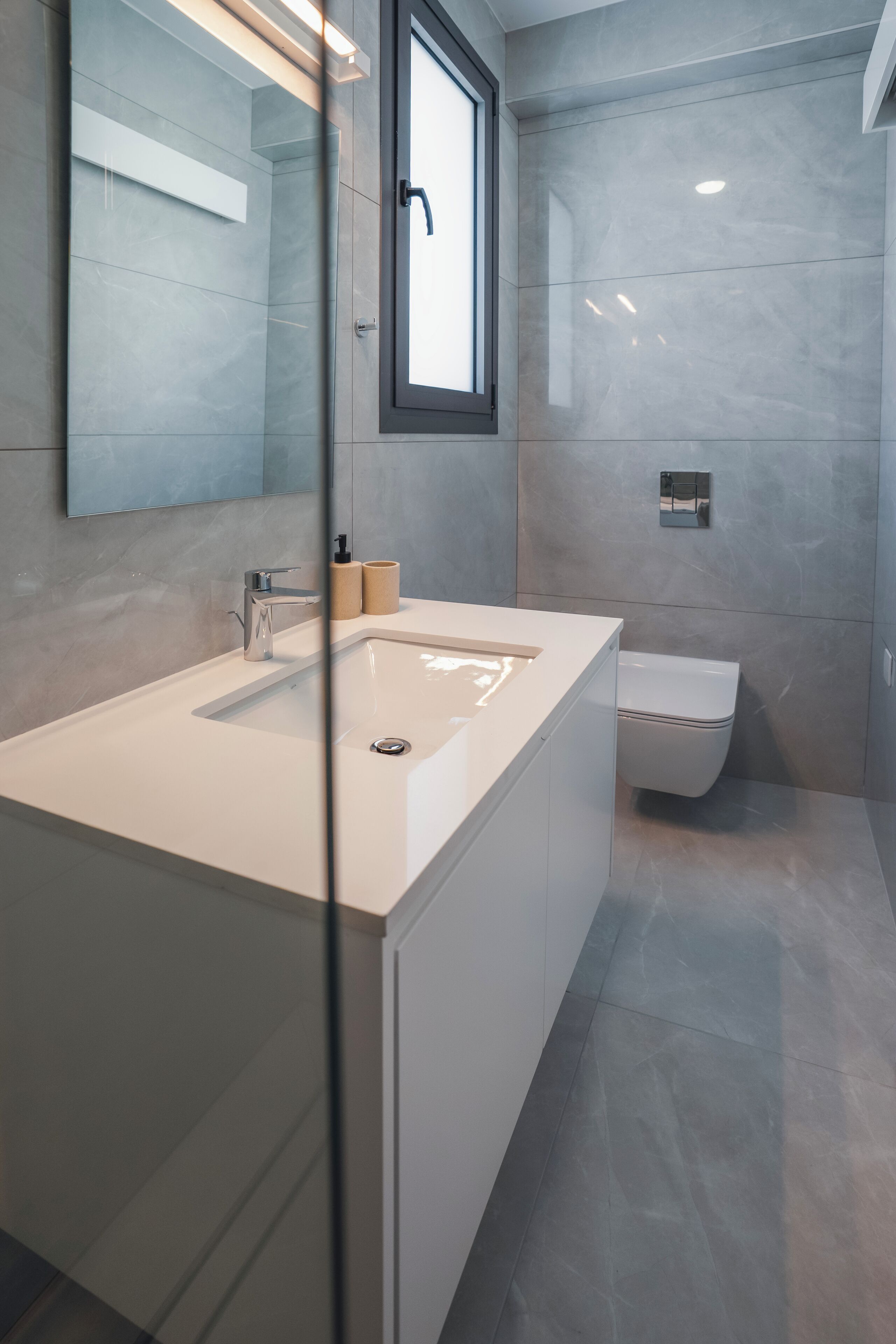 Een moderne badkamer met een grote spiegel, een wastafel en een toilet.