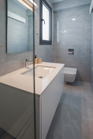 A modern bathroom with a large mirror, a sink, and a toilet. - Mira Paphos - 2bdr Apartment With Private Terrace (Paphos)