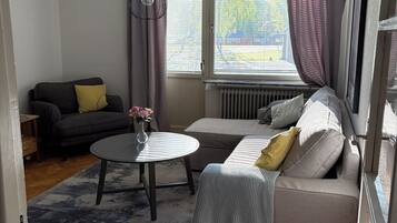 Een woonkamer met een bank, een rond bijzettafeltje en een radiator.