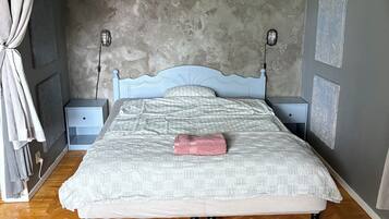Ein Schlafzimmer mit einem Bett, zwei Nachttischen, einem Teppich und einem Vorhang.