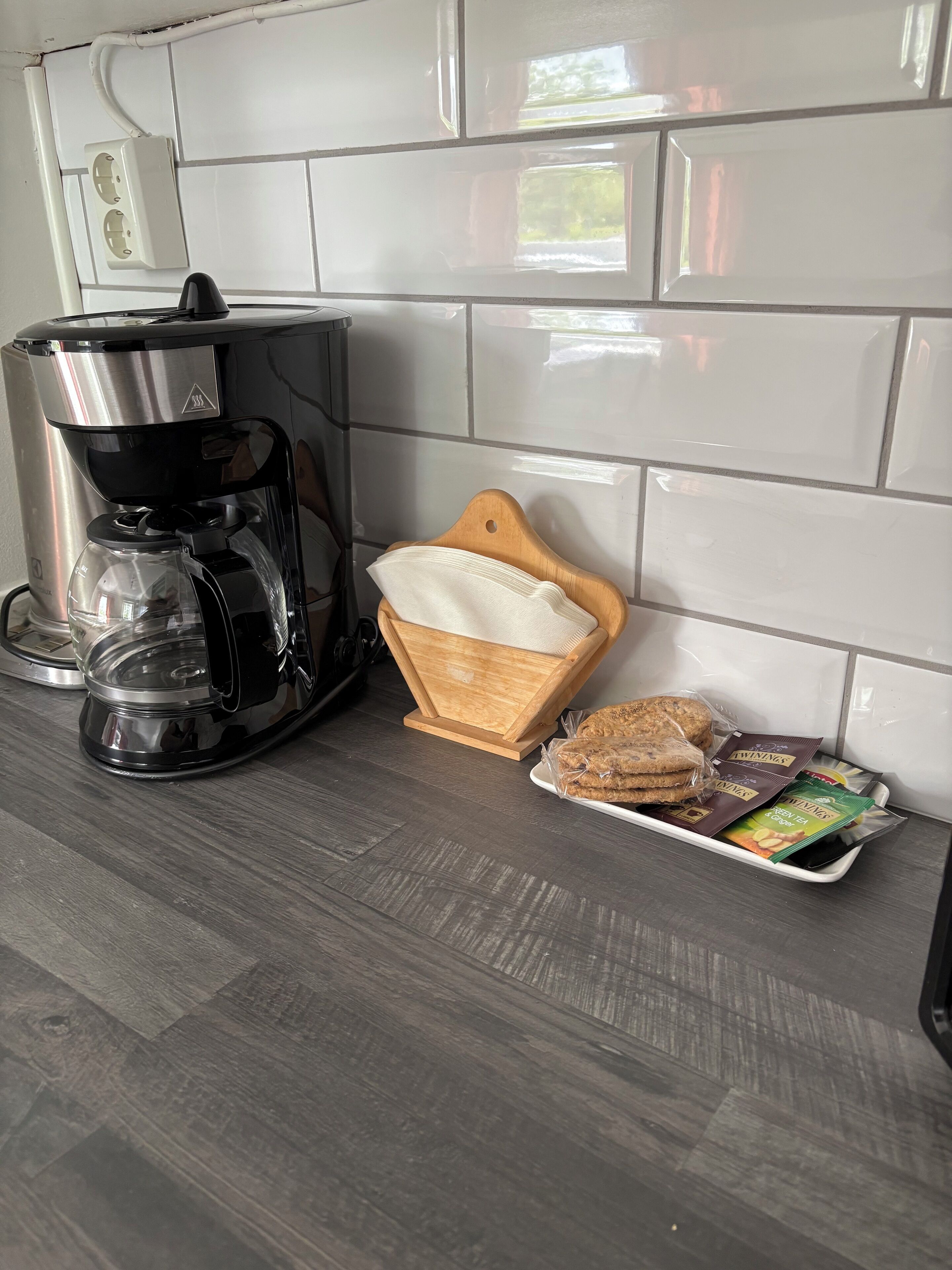 Eine Küche mit Kaffeemaschine, einem Holztisch und einer Platte mit verpackten Snacks.