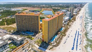 Un hotel costero con varios edificios altos, una playa y una piscina.