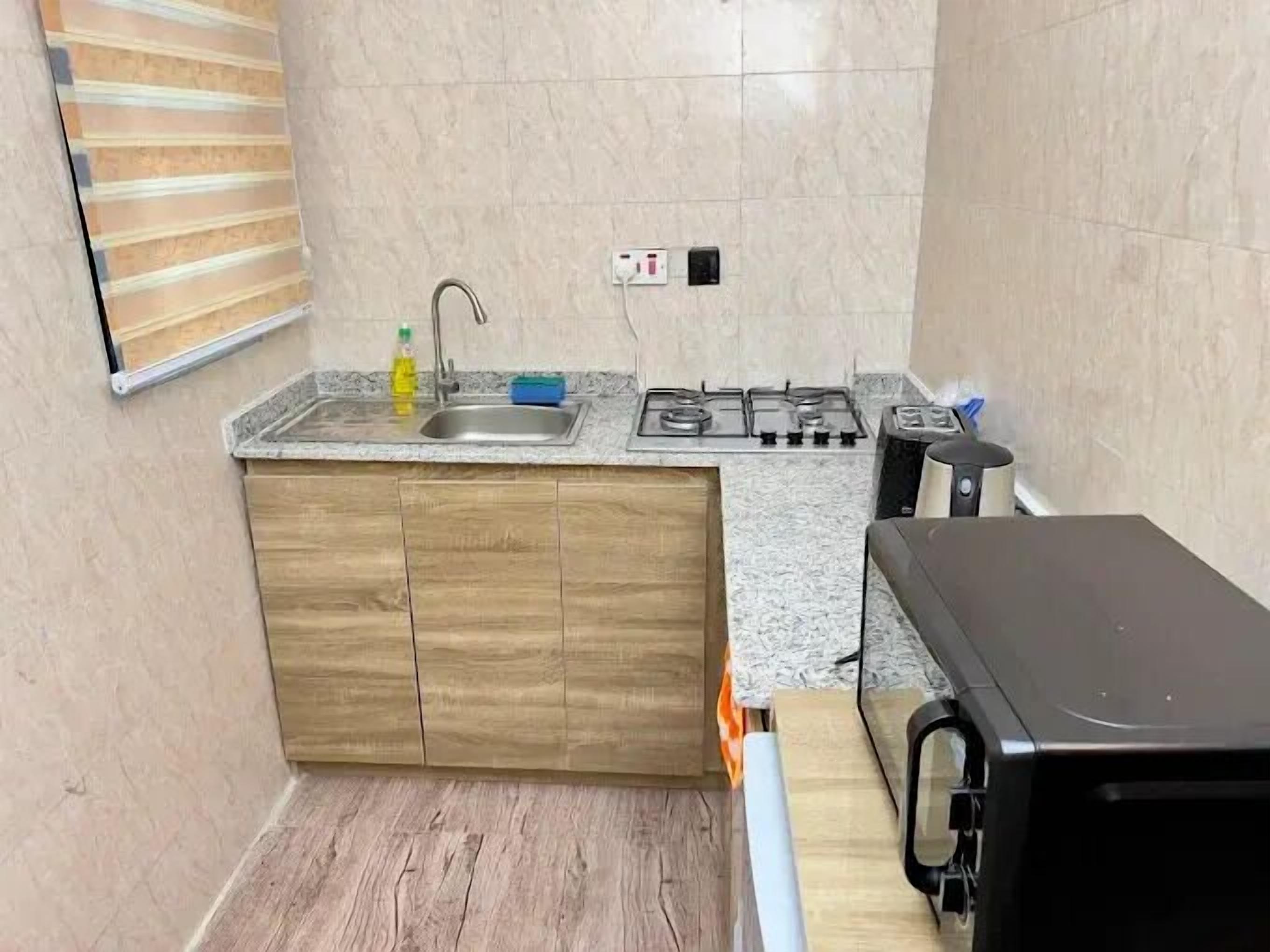 A compact kitchen with a sink, stove, and wooden cabinets.