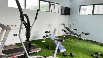 Gimnàs amb equipament d'exercici, incloent cintes de córrer i aparells de musculació, sobre un terra verd.