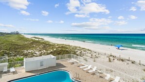 A beach view with a swimming pool, lounge chairs, and a fence. - Beachfront Studio, Pool (Panama City Beach)