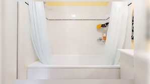 A modern bathroom with a bathtub, a towel rack, and a small shelf with toiletries. - Private Room in Lille Centre (Lille)