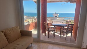 Un balcon avec vue sur la mer, une table à manger avec des chaises et un canapé.