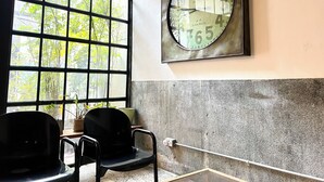 A room with a large window, two chairs, and a wall-mounted clock. - Hour Roots (Tainan)