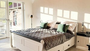 A bedroom with a bed, bedside table, and a view of the outside.