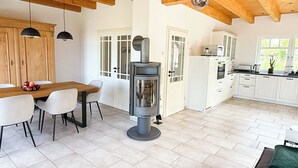 A modern kitchen with white cabinets, a central stove, and a dining area with a wooden table and chairs.