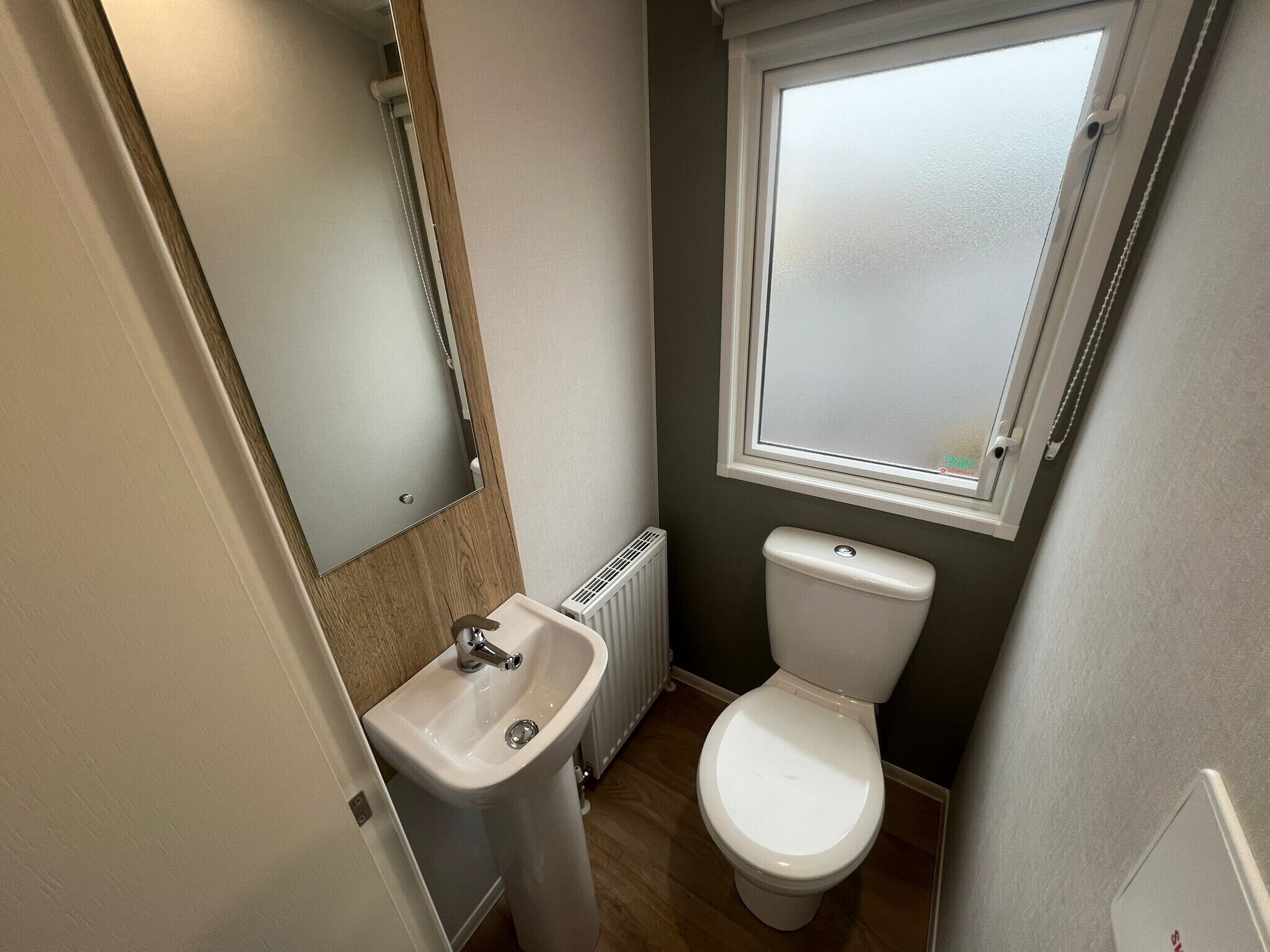Un baño pequeño con lavamanos, inodoro y ventana sobre el inodoro.