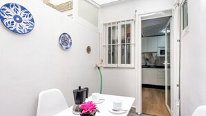 A small, white-walled room with a table and chairs, a coffee maker, and a potted plant.