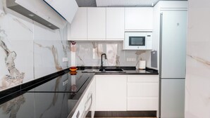 A modern kitchen with white cabinets, a black countertop, and a built-in microwave.