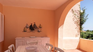 A dining area with a white table and chairs, a white cabinet, and a wall-mounted artwork. - Casa Cerbiatta al Molo 2 by Wonderful Italy (Arzachena)