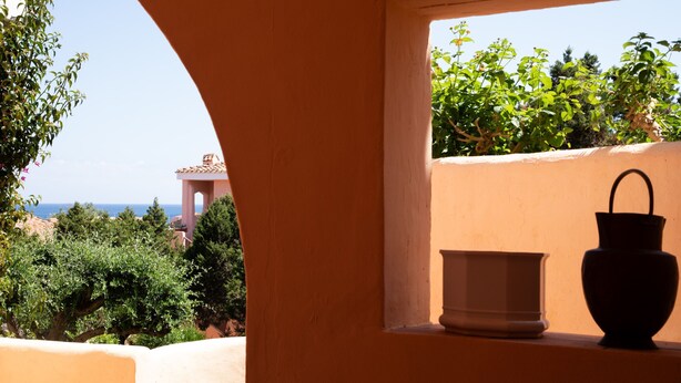 A balcony with a view of the sea and a building in the background. - Casa Cerbiatta al Molo 2 by Wonderful Italy (Arzachena)