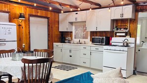 Een knus kamer in chaletstijl met een blauwe bank, houten wanden en een kitchenette.