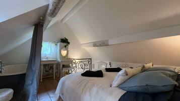 Une chambre à coucher avec un lit, une table de chevet, une commode, un miroir et une fenêtre avec des rideaux.