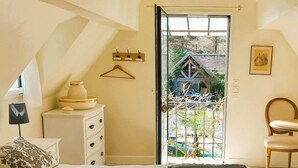 A bedroom with a bed, a dresser, a chair, and a door leading to a balcony.