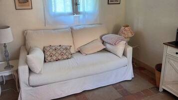 A white sofa with patterned cushions, a lamp, and two framed pictures on the wall.