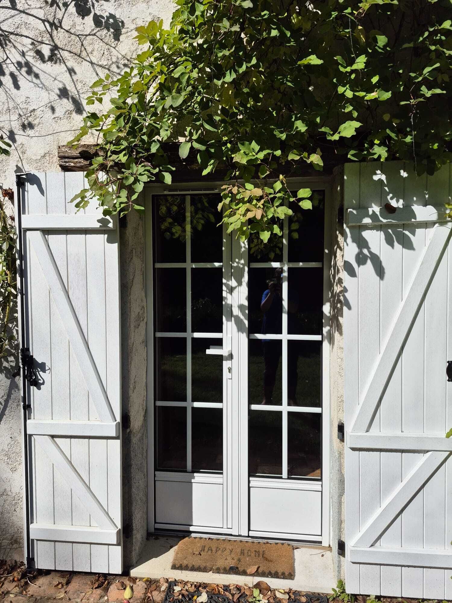 Una puerta de madera blanca con un panel de vidrio, incrustada en una pared de piedra.