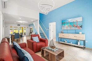A modern living room with a red sofa, a wooden coffee table, and a staircase leading to an upper floor.