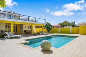 Una propiedad residencial con piscina, mobiliario exterior y balcón.